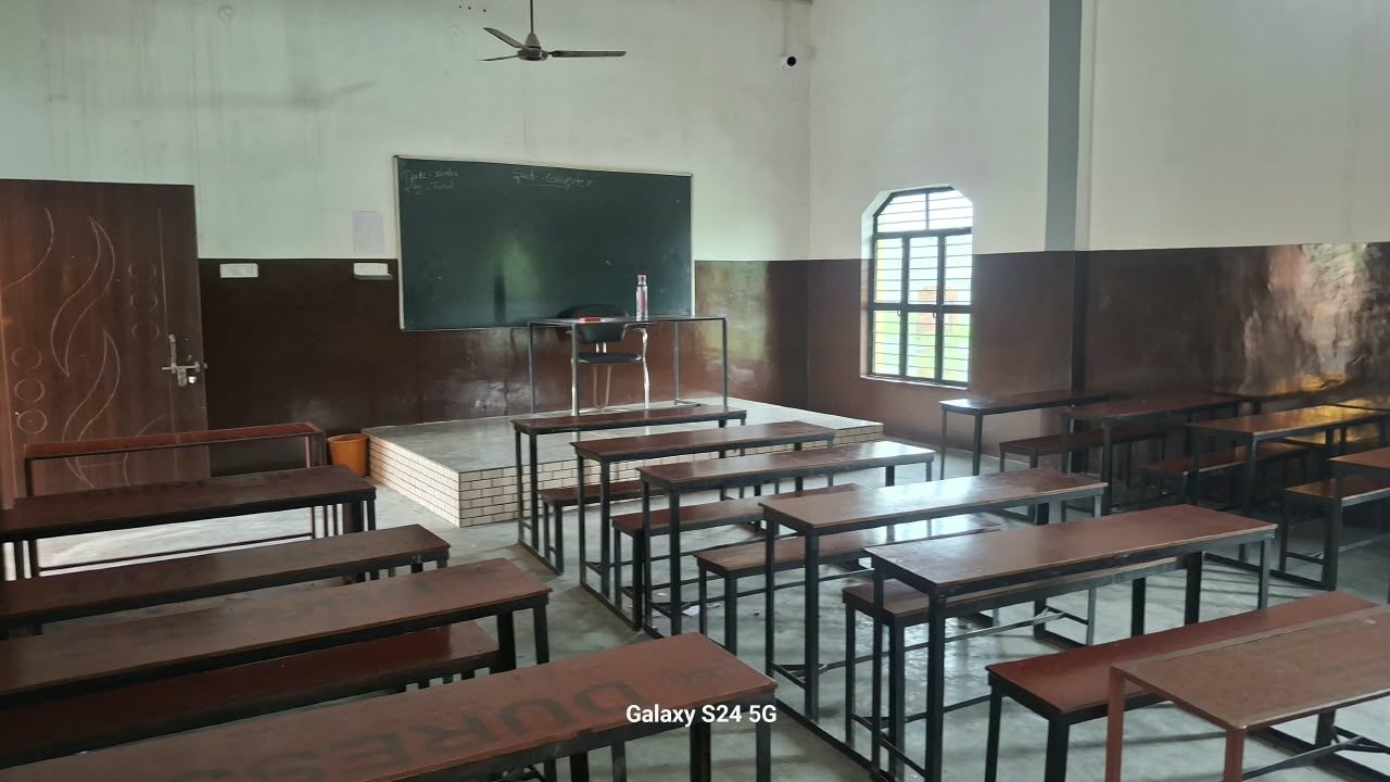 An empty classroom with benches and a blackboard