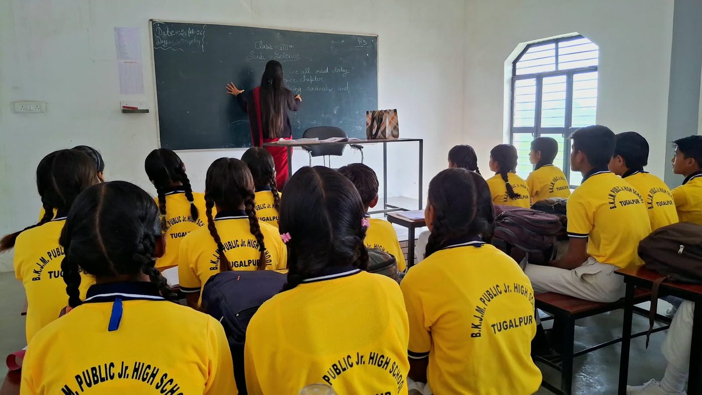 A teacher writing on the blackboard during a Class VIII science lesson